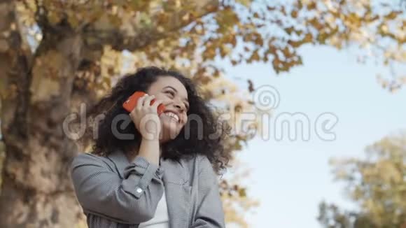 一个年轻的女孩一头深色卷发在城市公园里用电话视频的预览图