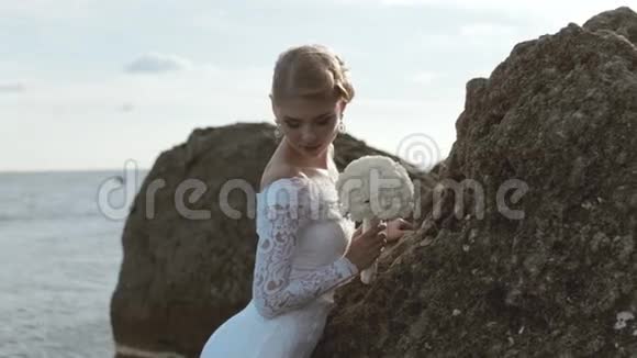 美丽的新娘在岩石上摆着花束视频的预览图