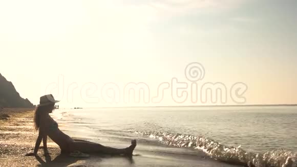 戴帽子的女人坐在海边视频的预览图