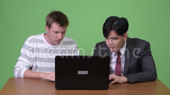 年轻的亚洲商人和年轻的斯堪的纳维亚商人与笔记本电脑合作视频的预览图