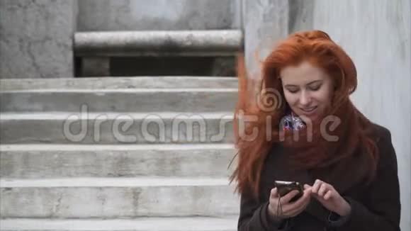 年轻的红头发女人带着智能手机视频的预览图