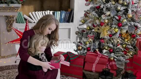 母女俩坐在圣诞树的遗嘱里拆开礼物家庭内部红色视频的预览图
