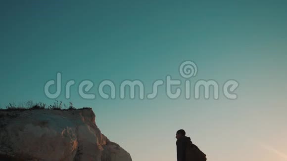 一位游客在日落探险时爬上山顶的剪影男人的轮廓视频的预览图