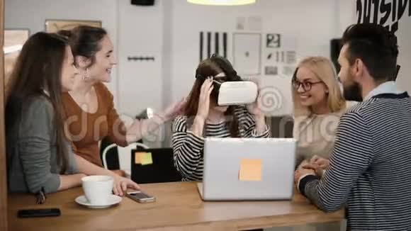 第一次体验虚拟现实眼镜年轻团队支持年轻漂亮的黑发女孩在现代创业办公室视频的预览图
