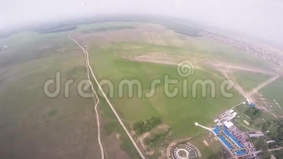 专业跳伞员准备降落在绿色的田野上夏天景观视频的预览图