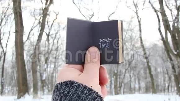 冬天的想法手拿一本书与文字背景的冬季公园视频的预览图