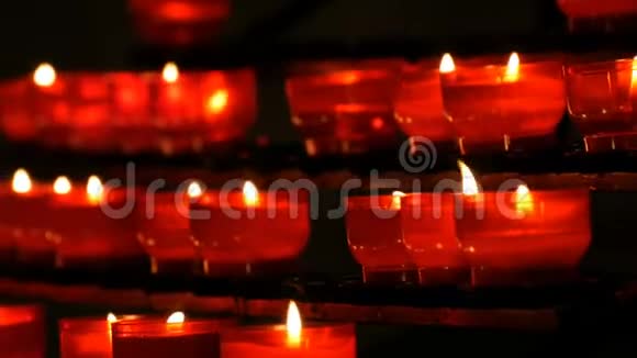 一排基督教祈祷红色的圆形蜡烛在黑暗中燃烧祈祷点燃祭祀蜡烛燃烧视频的预览图