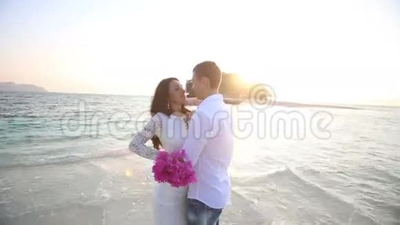 新娘和新郎拥抱在水中唾弃岛屿视频的预览图