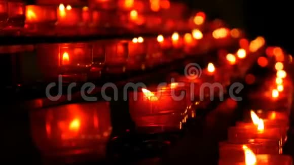 一排基督教祈祷红色的圆形蜡烛在黑暗中燃烧祈祷照明祭祀蜡烛近景视频的预览图