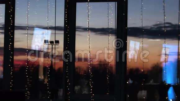 蓝色电视屏幕反射在装饰的大窗户上美丽的红日落在玻璃后面视频的预览图