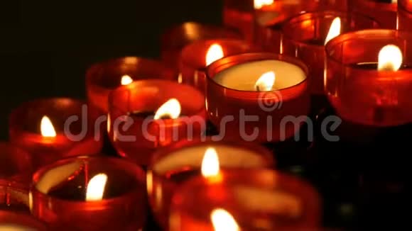 一排基督教祈祷红色的圆形蜡烛在黑暗中燃烧祈祷照明祭祀蜡烛近景视频的预览图