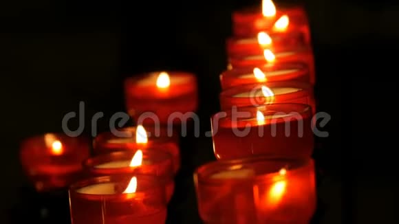 一排基督教祈祷红色的圆形蜡烛在黑暗中燃烧祈祷点燃祭祀蜡烛燃烧视频的预览图