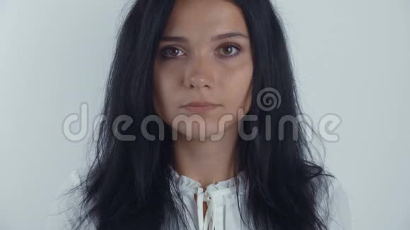 一幅年轻女子黑发女子在白色背景下看镜头的肖像视频的预览图