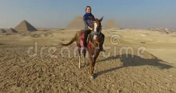 在吉萨金字塔广场骑马的快乐女人视频的预览图