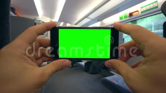 双手拿着装有绿色屏幕的手机视频的预览图