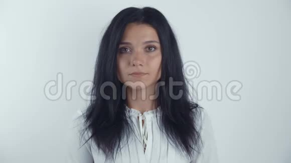 一幅年轻女子黑发女子在白色背景下看镜头的肖像视频的预览图