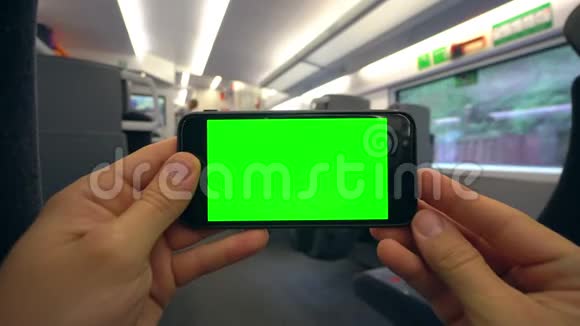 双手拿着装有绿色屏幕的手机视频的预览图