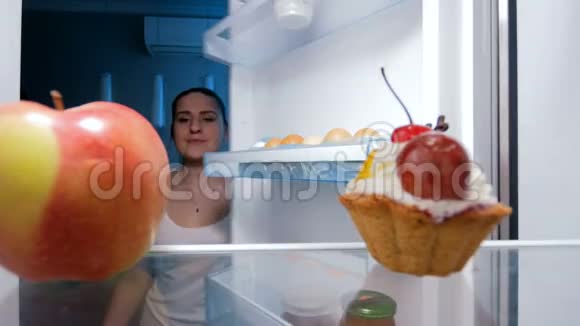 4k片年轻女子晚上从冰箱里取出甜糕点视频的预览图