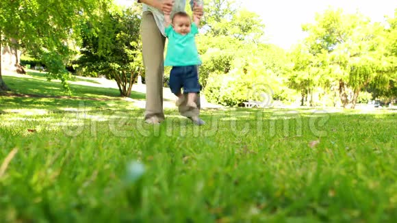 妈妈帮助小儿子在草地上散步视频的预览图