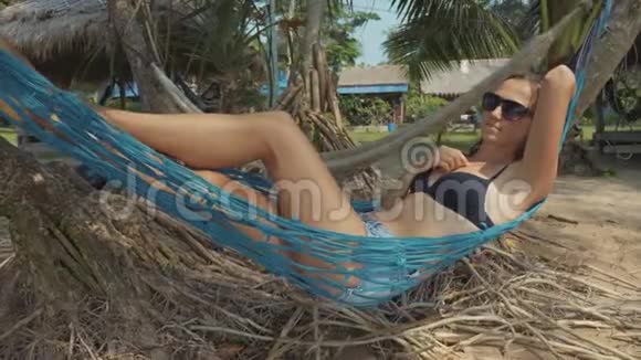 年轻快乐的女人慢动作躺在沙滩吊床上视频的预览图