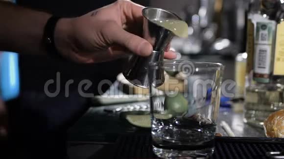 酒保正在做鸡尾酒在玻璃中加入第一种成分视频的预览图