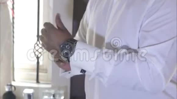 穿白色结婚衫的男人手里拿着手表视频的预览图