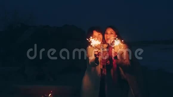 年轻的女人在夜晚的海岸上闪耀视频的预览图
