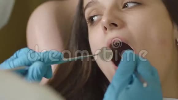 口腔和牙齿的检查在口腔检查过程中病人年轻女孩张开嘴的特写视频的预览图