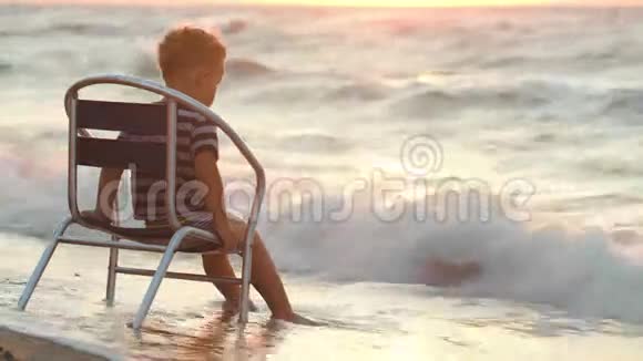 坐在海边椅子上的男孩视频的预览图