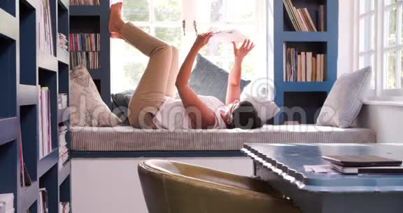 成熟的女人躺在家里的沙发上读书视频的预览图