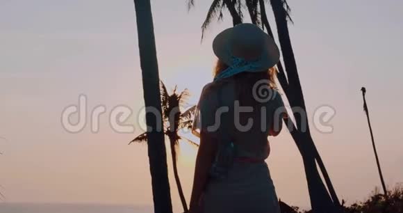 穿着连衣裙戴着帽子在热带海滩上轻松愉快视频的预览图