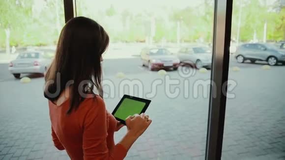 女人站在窗边在平板电脑上工作绿色屏幕视频的预览图
