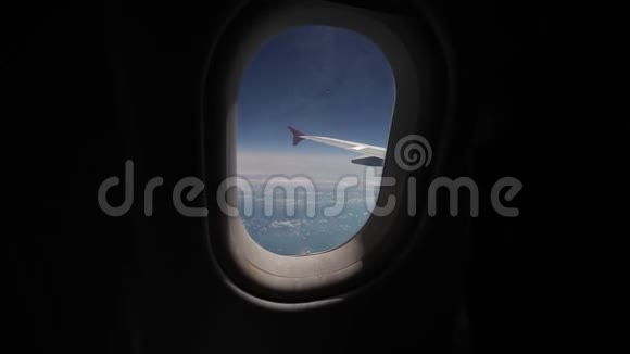 透过飞机的窗户观看蓝天和云彩用飞机的翅膀关闭飞机的窗户视频的预览图