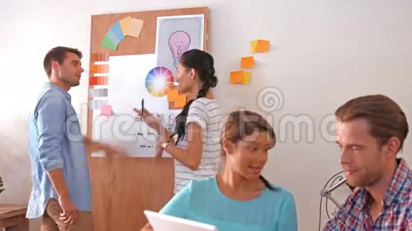 创意团队使用笔记本电脑而他们的同事则在观察颜色样本视频的预览图