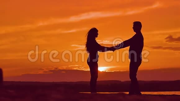 日落时分女孩和男孩牵着手在慢动作视频中盘旋视频的预览图