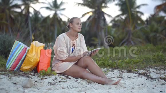 女人在海滩上用平板电脑购物后视频的预览图