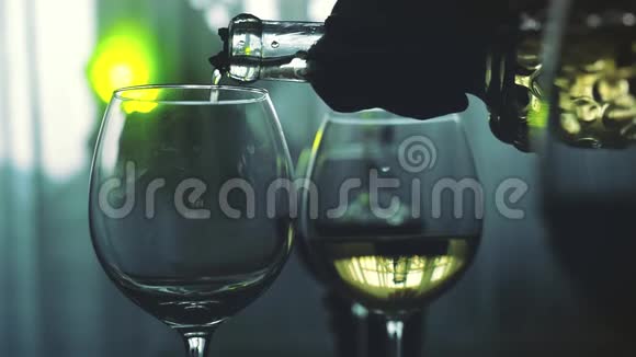 在节日桌上白葡萄酒缓慢地倒入玻璃杯中背景上有灯光1920x1080视频的预览图