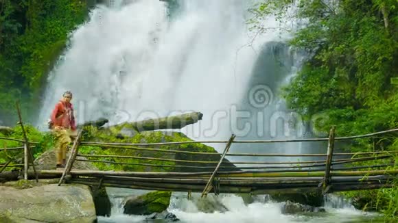 游客在瀑布的背景下过河泰国DoiInthanon国家公园视频的预览图
