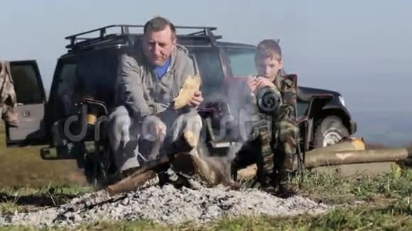 父子俩在篝火旁吃烤面包视频的预览图
