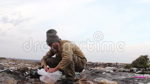 肮脏的流浪汉坐在垃圾桶里吃面包视频的预览图