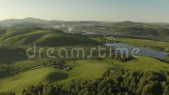 空中无人机镜头在日出的柔和光线下飞越森林田野和河流的秋山村视频的预览图