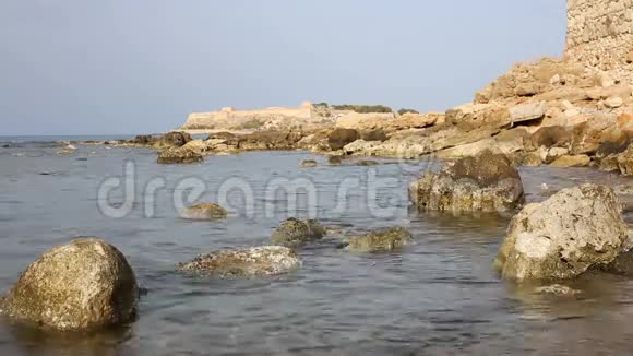 一条蓝色海洋的岩石海岸线背景上有古老的莱西莫要塞视频的预览图
