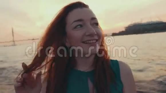 穿着绿松石衣服的年轻女孩在摩托艇上摸头发日落浪漫的夜晚视频的预览图