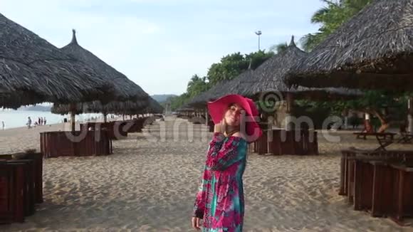 穿着长裙的女孩在海滩上打着雨伞摆姿势视频的预览图