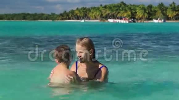 母亲和儿子在清澈的海水中玩耍视频的预览图