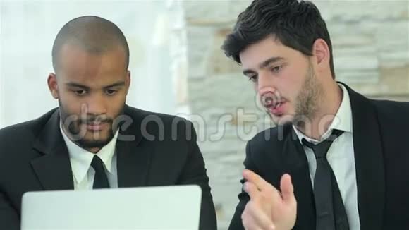 两个年轻人在讨论笔记本电脑上的信息视频的预览图