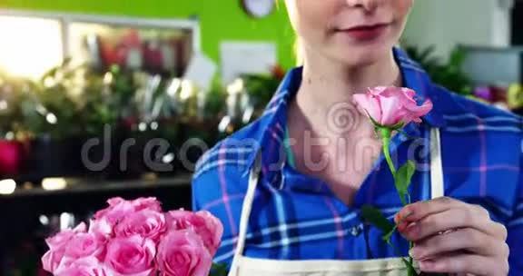 漂亮的女花店闻着一束粉红色的玫瑰视频的预览图