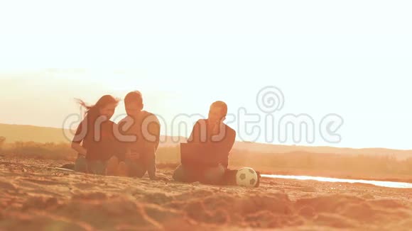 男人在电话里说话女人和一个男人坐在沙滩慢动作视频里视频的预览图