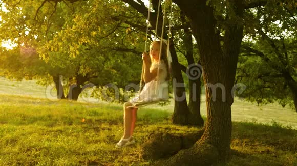 孩子在公园里荡秋千年轻女孩在橡木树枝上的绳索秋千上摆动少女喜欢在秋千上飞行视频的预览图