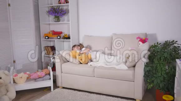 美丽的小女孩睡前躺在沙发上视频的预览图